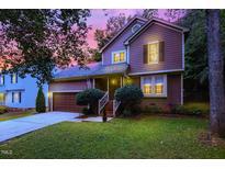 Two-story house with brown siding, attached garage, and landscaped lawn at 1400 Deltona Dr, Raleigh, NC 27615