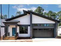 Contemporary home with modern architecture, dark window frames, and gray garage door at 2662 Sledge Rd, Louisburg, NC 27549
