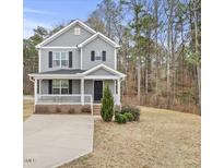 Two-story gray house with white trim, front porch, and driveway at 3928 Mike Levi Ct, Raleigh, NC 27610