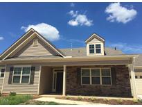 Tan two-story house with brown brick accents and a covered porch at 13 E Milan Ct, Clayton, NC 27527