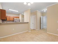 Bright living room showcasing neutral carpet, white trim, and an open floorplan flowing into the kitchen at 2621 Oldgate Dr # 105, Raleigh, NC 27604