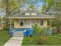 Charming bungalow featuring a cozy front porch, light yellow exterior, and lush green lawn at 1108 Taylor St, Durham, NC 27701