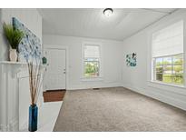 Bright living room with neutral carpet, white walls, and natural light, with modern decor and entry door at 1108 Taylor St, Durham, NC 27701