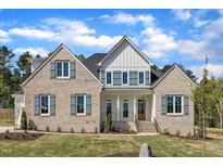 Beautiful brick home with gray shutters, white siding, manicured lawn, and elegant front entrance at 3803 Bennett Grove Dr, Wake Forest, NC 27587