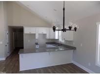 Bright kitchen features granite countertops, white cabinetry, and modern pendant lighting at 104 Halifax Rd, Louisburg, NC 27549