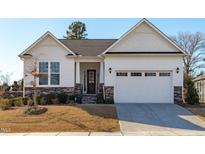 White house with gray stone accents, two-car garage, and landscaping at 1177 St. Cloud Loop, Apex, NC 27523