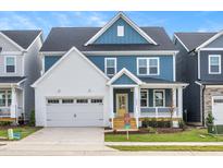 Two-story home with blue and white siding, a front porch, and a two-car garage at 1601 Merry Meadow Ln, Wendell, NC 27591