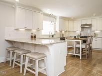 Bright kitchen features white cabinets, granite countertops, a breakfast bar with seating, and stainless steel appliances at 505 Annandale Dr, Cary, NC 27511