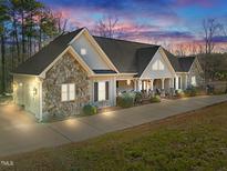 Charming ranch-style home features a stone facade, covered porch, and a long driveway with ample parking at 413 Johnson Town Rd, Zebulon, NC 27597
