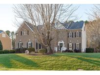 Two story brick home with landscaping and large tree in front at 7828 Percussion Dr, Apex, NC 27539