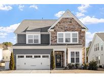 Two-story home with stone and shingle accents, two-car garage, and landscaping at 1109 Timbercut Dr, Durham, NC 27703