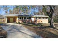 Ranch style home with brick facade, driveway, and mature trees at 1202 Vandora Ave, Garner, NC 27529