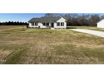 Newly constructed home with light-colored siding, gray roofing, and a spacious lawn at 63 Harvest Hills Ln, Dunn, NC 28334