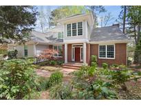 Charming brick and siding home featuring a red door, beautiful windows and a well-maintained landscaped yard at 76527 Rice, Chapel Hill, NC 27517