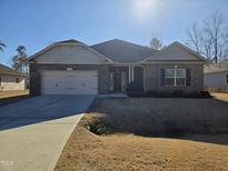 Brick house with 2-car garage, and a well-maintained lawn at 78 Falls Of The Cape Dr, Lillington, NC 27546