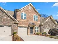 Brick front exterior of charming townhome with two-car garage and landscaped yard at 1099 Talisker Way, Burlington, NC 27215