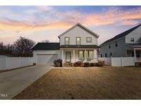 Two-story farmhouse features white siding, a front porch, and a two-car garage at 308 W Hill St, Benson, NC 27504