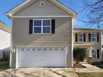 Two-story house with beige siding, white garage door, and landscaping at 1611 Copper Cir, Mebane, NC 27302