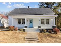 Charming home with white exterior, blue door with wreath, and a well-maintained yard at 205 Spring St, Louisburg, NC 27549