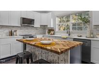 Charming kitchen featuring white cabinets, stainless steel appliances, and unique butcher block island with seating at 205 Spring St, Louisburg, NC 27549