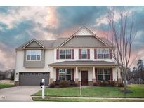 Charming two-story home featuring a well-manicured lawn, attached garage, and inviting front porch area at 241 Fair Oaks Ct, Mebane, NC 27302