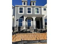 Charming gray two-story home boasts a welcoming front porch and elegant black wrought iron fence at 498 Traditions Grande Blvd # 23, Wake Forest, NC 27587