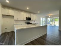 Modern kitchen featuring white cabinets, stainless steel appliances, and a large island with granite countertops at 500 Traditions Grande Blvd # 22, Wake Forest, NC 27587