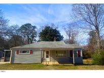 Charming single-story home featuring a cozy porch and mature trees at 5324 Rock Quarry Rd, Raleigh, NC 27610