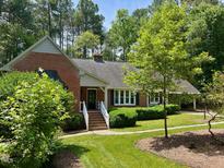 Charming brick home with well-maintained landscaping, white stairs leading to the front door, and mature trees surrounding the property at 1210 Huntsman Dr, Durham, NC 27713