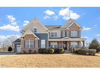 Beautiful two-story home featuring a brick and siding facade, covered porch, and manicured landscaping at 20 Hickory Downs Dr, Siler City, NC 27344