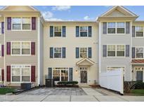 Three-story townhome with neutral siding, shutters, and a paved patio at 2225 Raven Rd # 107, Raleigh, NC 27614