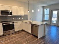 Modern kitchen boasts stainless steel appliances, granite countertops, and sleek white cabinetry at 2313 Gathering Square Ct # 2313, Fuquay Varina, NC 27526