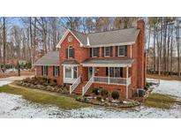 Brick two-story house with a white porch, landscaping, and snowy yard at 4139 Somerset Dr, Oxford, NC 27565