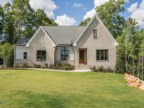 Brick home with a pitched roof, large windows, and a landscaped lawn at 64 W Beech Slope Ct, Chapel Hill, NC 27517
