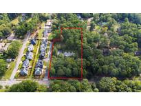 Aerial view of a house nestled in a wooded lot, surrounded by other homes at 715 Powell Dr, Raleigh, NC 27606