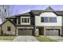 Two-story townhome with stone and shingle accents, two-car garage, and landscaped yard at 962 Double Helix Rd, Apex, NC 27523