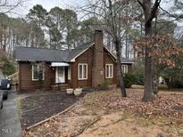 Brown wood siding house with brick base and mature trees at 11 Donnybrook Ct, Durham, NC 27713