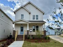 Charming two-story home with a inviting front porch and a light blue front door at 129 Mossy Falls Way, Wendell, NC 27591