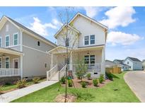 Charming two-story white home featuring a welcoming front porch and well-manicured lawn at 129 Mossy Falls Way, Wendell, NC 27591