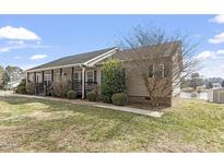 Ranch home with brown siding, front porch, and landscaped yard at 133 John Winstead Rd, Louisburg, NC 27549