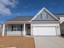 Charming single-story home with a two-car garage, covered porch, and classic architectural details under a blue sky at 46 Steppe Way, Garner, NC 27529