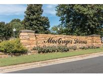 Stone community entrance sign for MacGregor Downs with beautiful landscaping and a clear blue sky above at 501 Queensferry Rd, Cary, NC 27511
