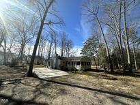 View of the home exterior showing the white siding, chimney, and partial driveway at 8421 Falcon Crest Cir, Angier, NC 27501