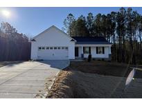 White house with two-car garage and landscaping at 241 Magnolia Run Way, Benson, NC 27504