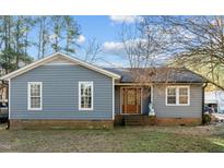 Ranch home features gray siding, a wood front door, and a landscaped yard at 6516 Battle Bridge Rd, Raleigh, NC 27610
