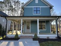 Charming two-story home showcasing a covered porch with white pillars and teal siding at 715 Heidelberg St, Durham, NC 27704