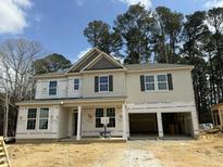 New construction home with a two-car garage showcasing a modern design against a backdrop of mature trees at 752 Portland Rose Dr, Knightdale, NC 27545