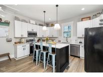 Bright kitchen features white cabinets, subway tile backsplash, stainless steel appliances and kitchen island with breakfast bar at 1006 W Broad St, Dunn, NC 28334