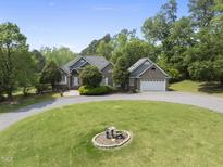 Charming brick home with well-manicured lawn and a circular driveway showcasing its curb appeal at 265 Verde Rd, Apex, NC 27523