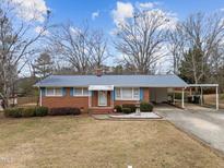 Brick ranch house with carport and landscaped lawn at 312 Holloway St, Cary, NC 27513